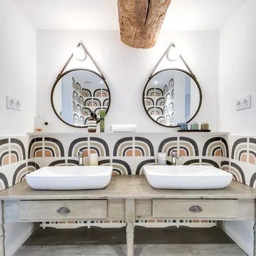 Salle de bain moderne avec miroir rond et mur carrelé graphique